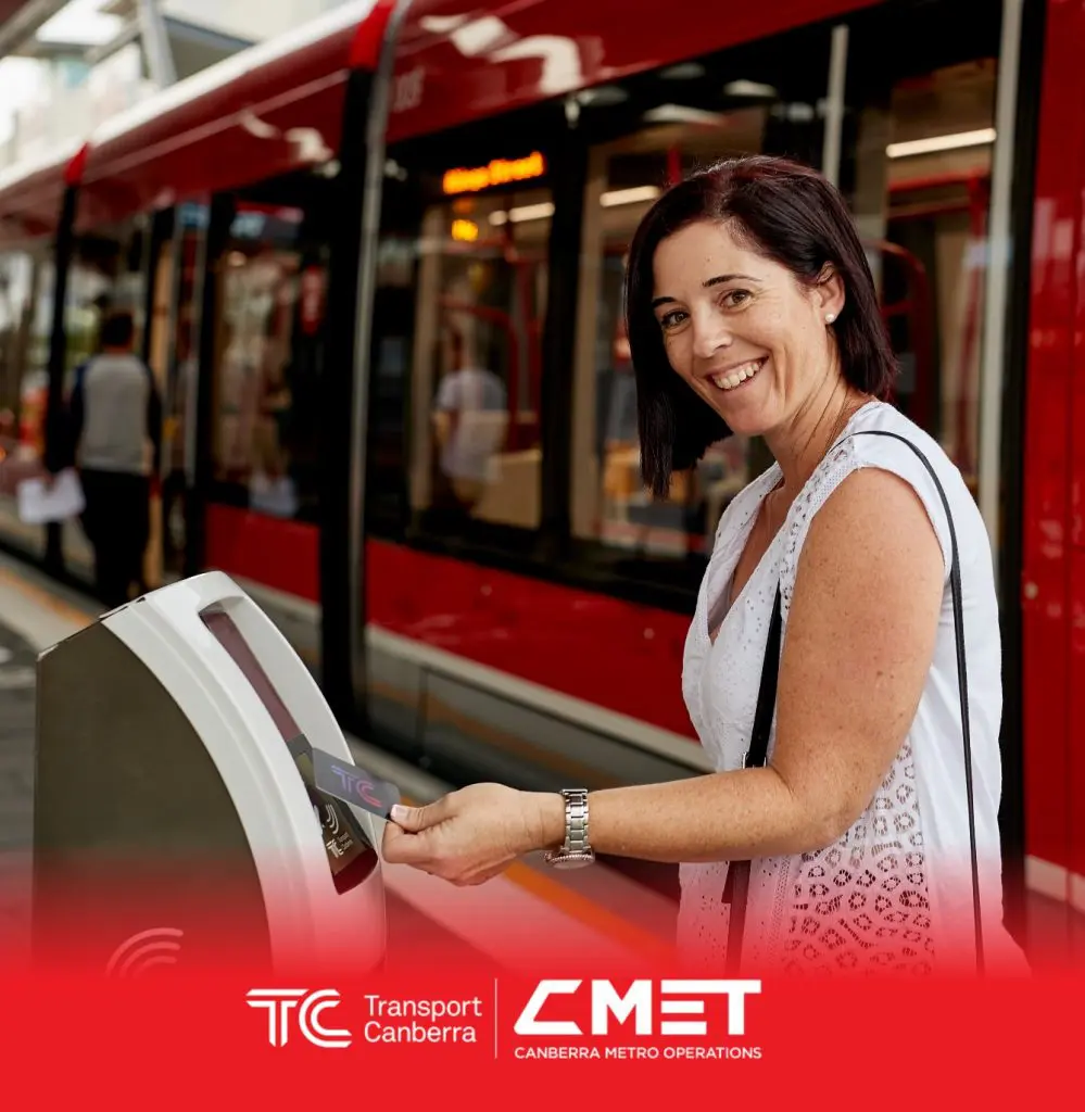 A lady smiling and tapping on the MyWay card at light rail stop